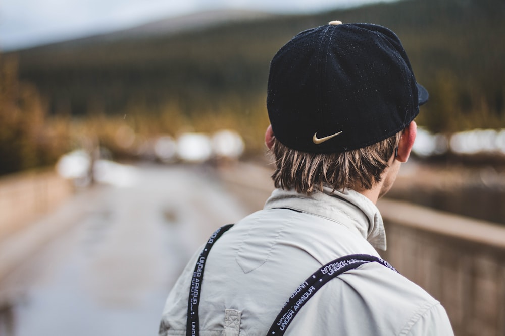 selective focus photograph of person in gray collared shirt and black Nike curve-brimmed cap