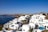 A picturesque Greek island with clear blue waters and white buildings.