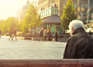 man sitting on brown wooden bench