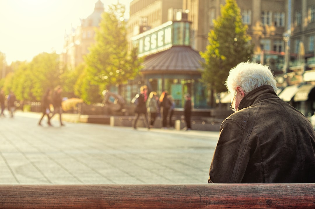 man sitting on brown wooden bench,