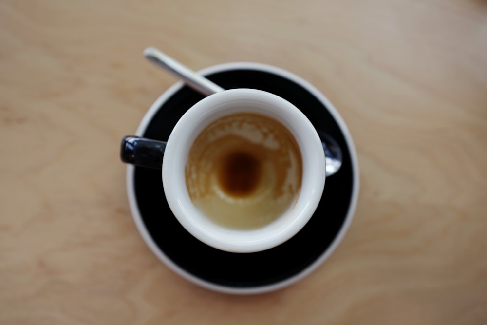 Café en taza en platillo al lado de la cuchara