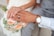 Close-up of intertwined hands with wedding rings, surrounded by delicate floral details.