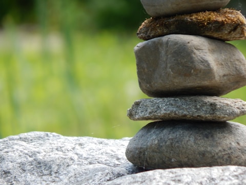 A close-up of balanced stones surrounded by green leaves.