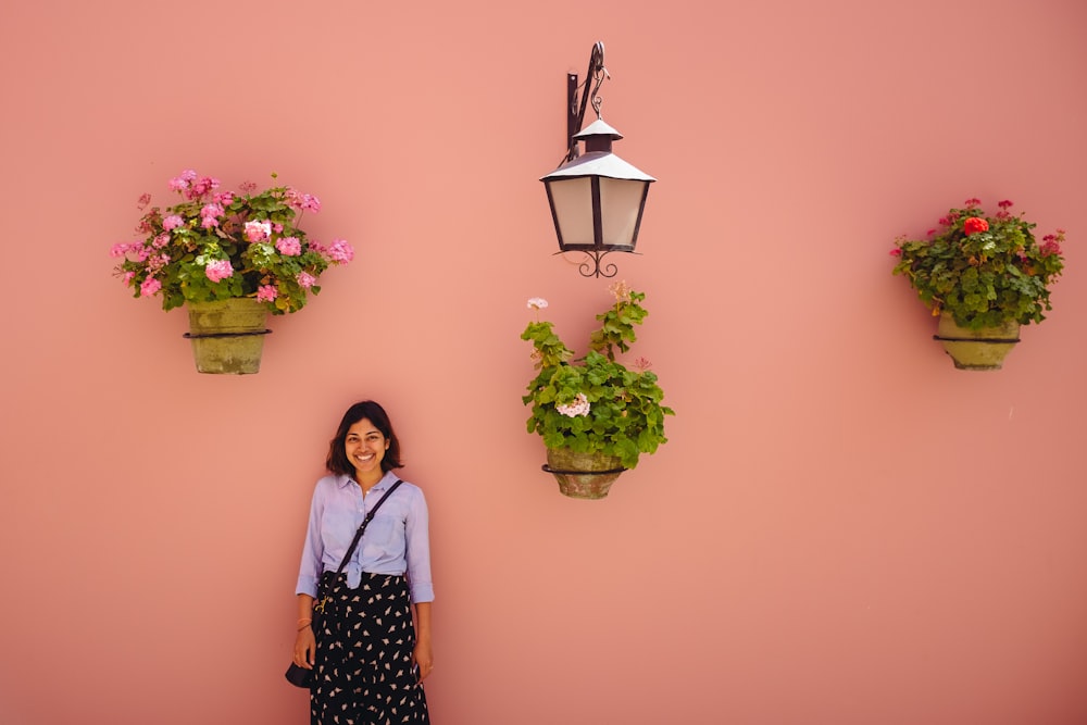 woman in white and black long sleeve shirt standing beside pink flower