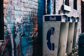 white and black Bell phone booth beisde concrete bricked wall with graffiti