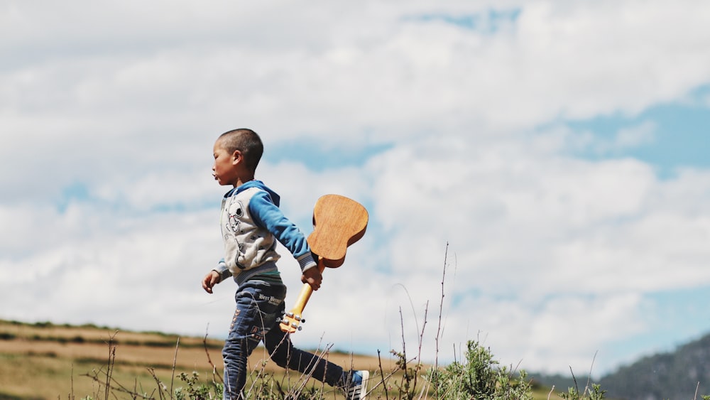 boy running while holding ukelele