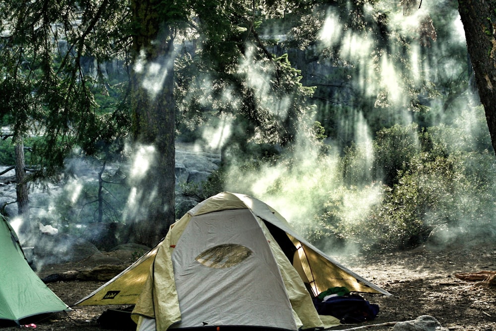 숲 한가운데에 있는 흰색과 노란색 캠핑 텐트
