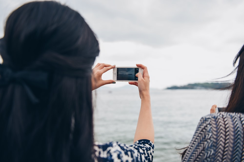 mulher usando smartphone na frente da água do mar