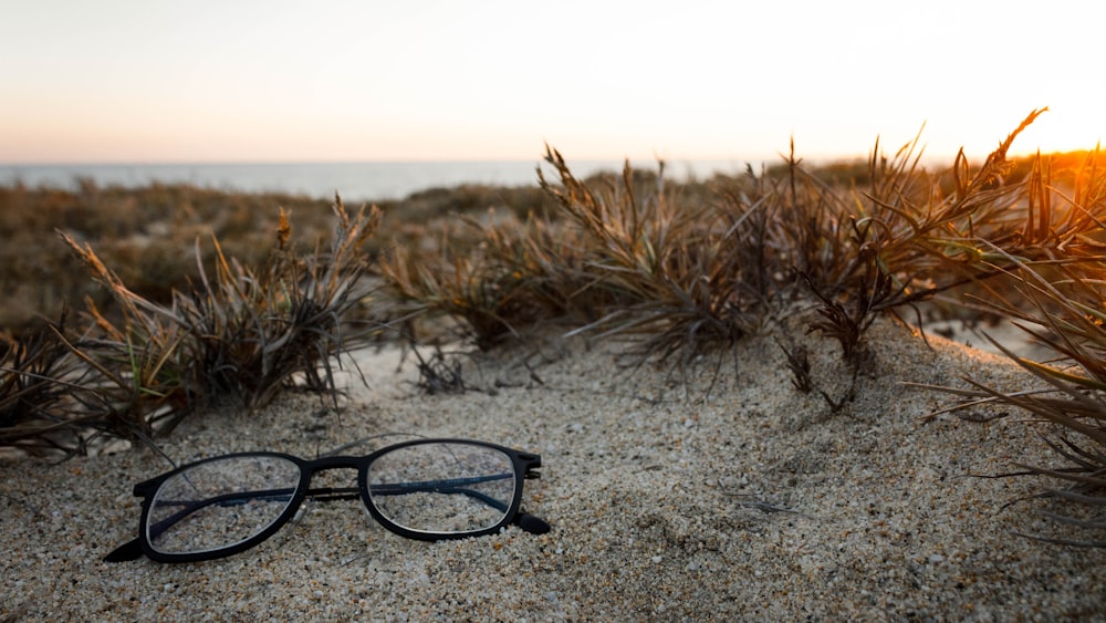 clear eyeglasses with black frames on sand