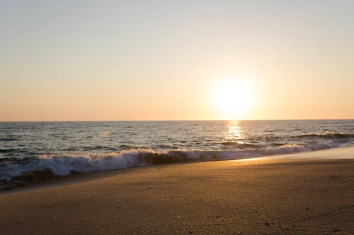 A serene golden sunset over a pristine white sand beach with gentle waves.