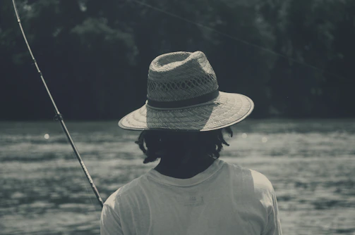 A close-up of a breathable fishing hat with a neck flap by a sparkling river