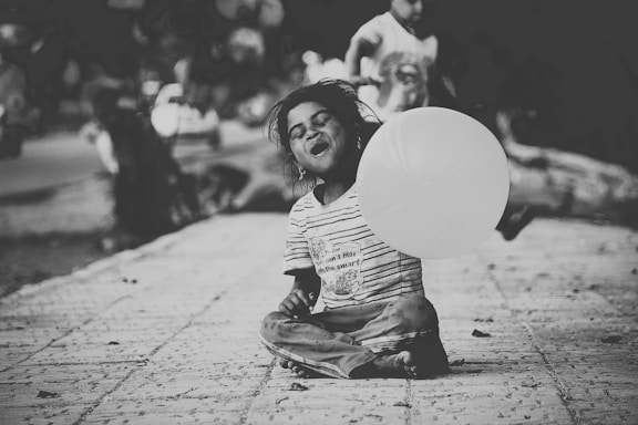 A cheerful child holding a colorful balloon, smiling brightly in a sunny park.