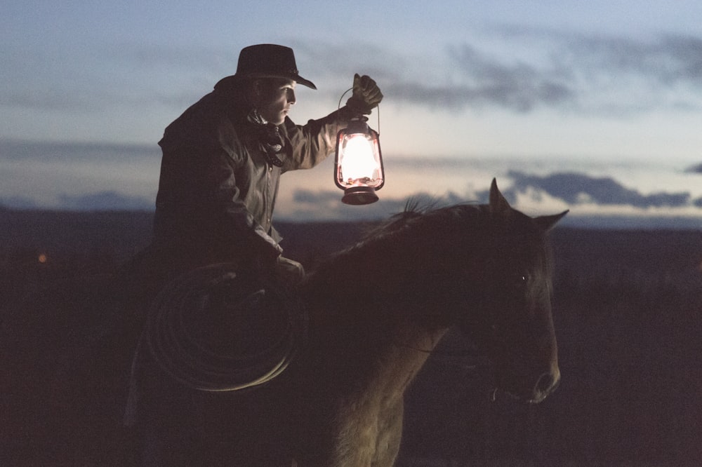 man riding horse holding lantern