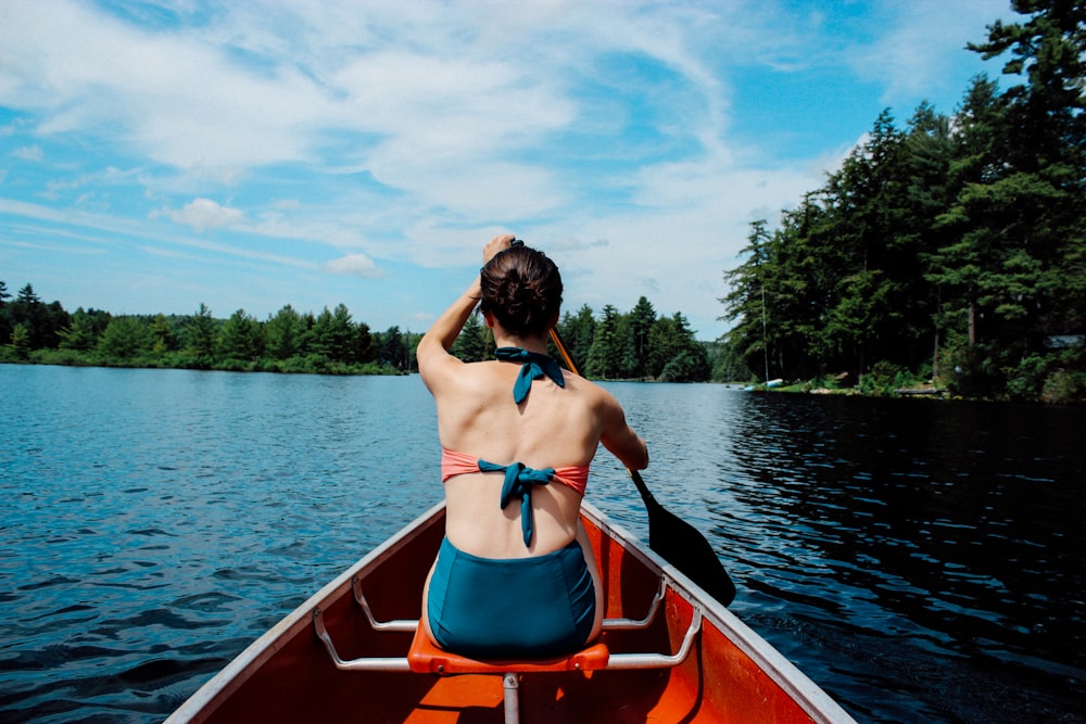 woman riding on boat while paddling under blue sky during daytime