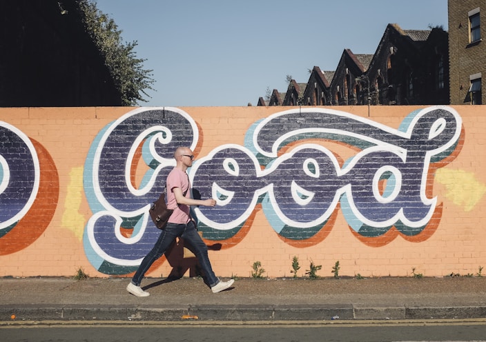 man walking beside graffiti wall