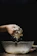 A close-up of hands mixing natural ingredients in a glass bowl.