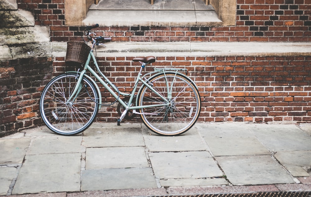 Foto de una bicicleta azul estacionada en una pared de ladrillo gris