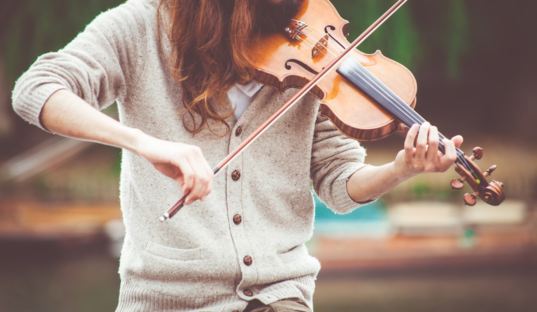 person playing brown violin, Outdoors violinist in a sweater