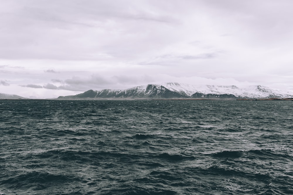 body of water near mountain covered with snow