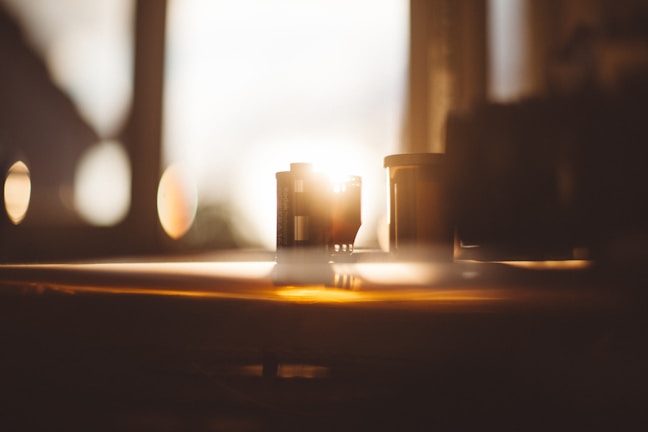 Stacks of aged film canisters with faded labels under soft, warm lighting.