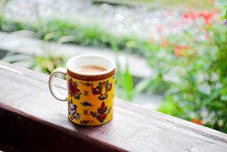 A vibrant ceramic coffee mug filled with steaming coffee, sitting on a colorful patterned cloth.