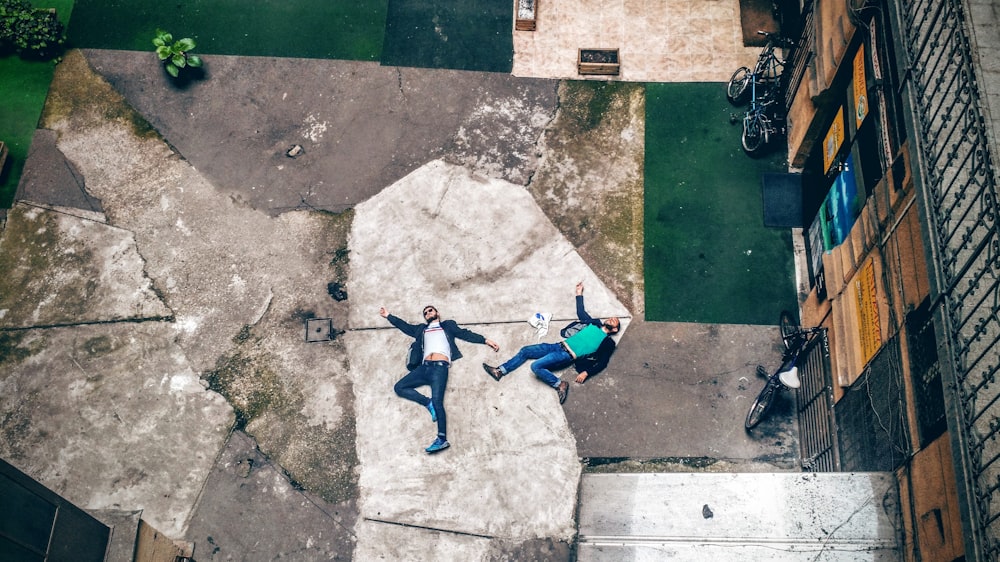 Vista aérea de dos hombres tendidos sobre el pavimento de hormigón
