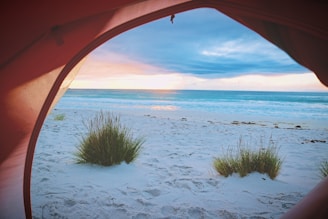 A breathtaking view of Pulau Payung’s turquoise waters at sunset with cozy glamping tents nestled among lush greenery.