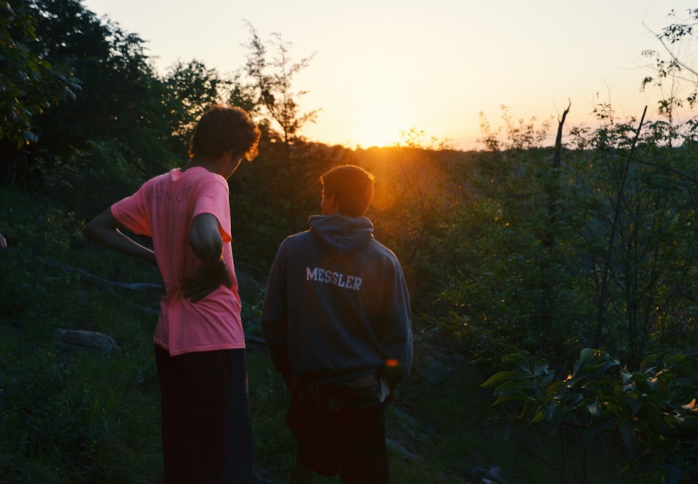 two men standing near green trees