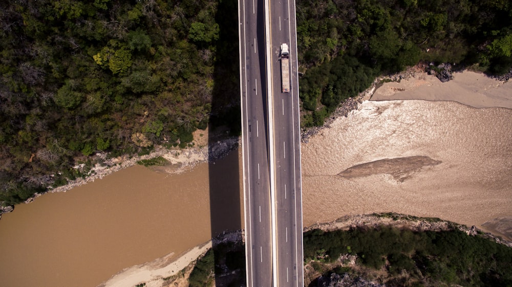 camion bianco sulla strada di cemento grigio vicino agli alberi durante il giorno