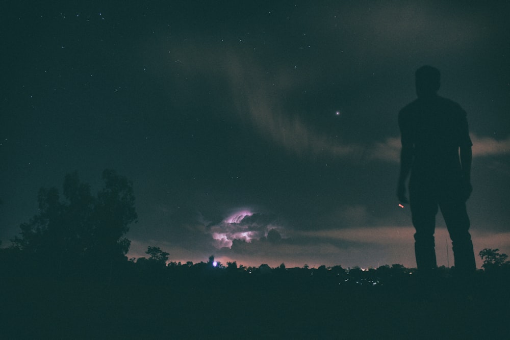 silhouette of man standing under night sky