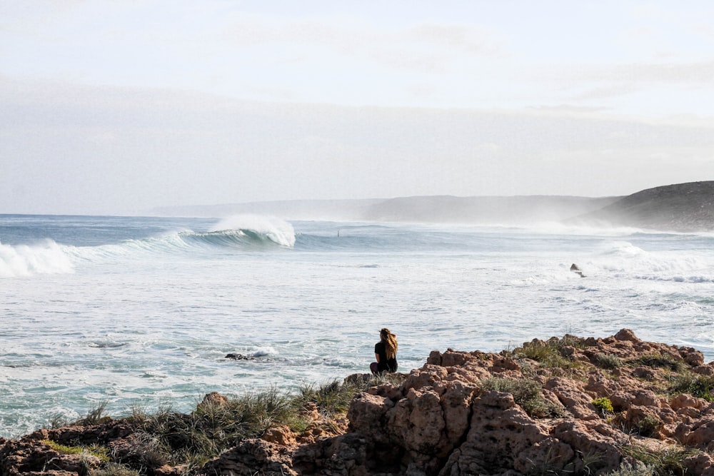 woman sitting on rock near the beach