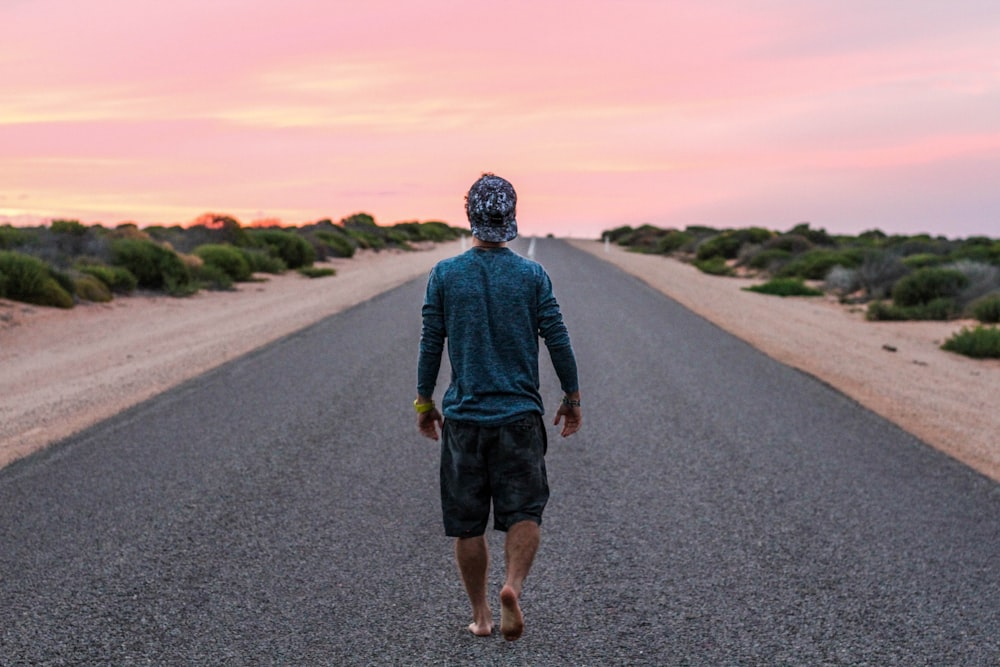 uomo che cammina sulla strada di cemento grigio