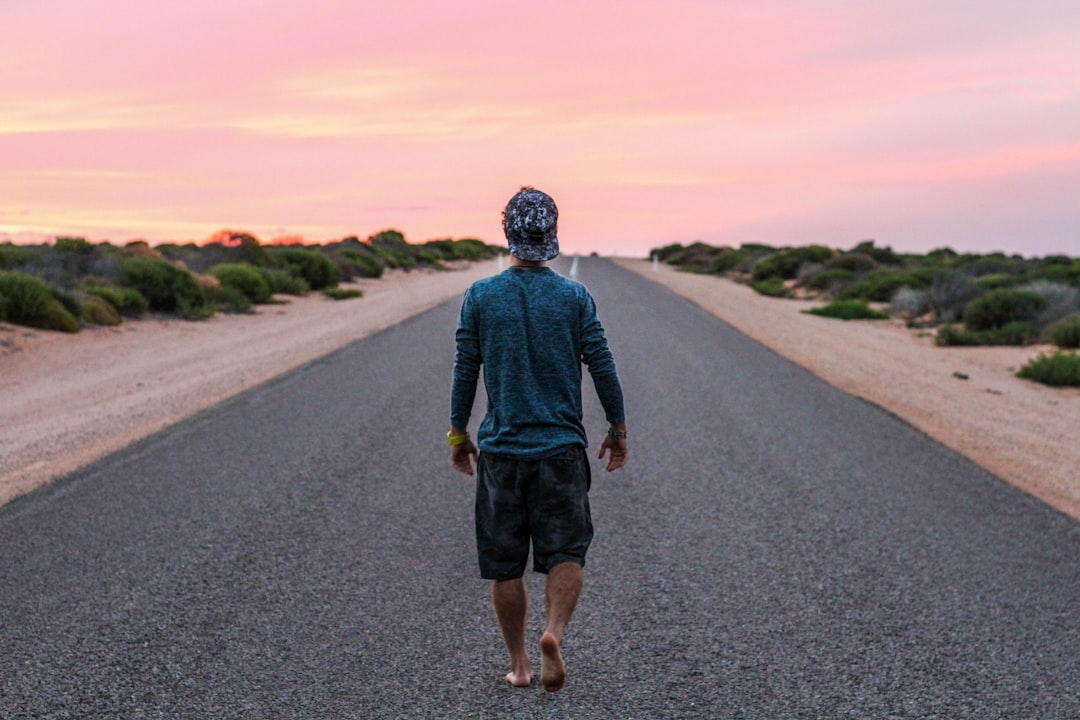 man walking on gray concrete road, Lone man on an asphalt road