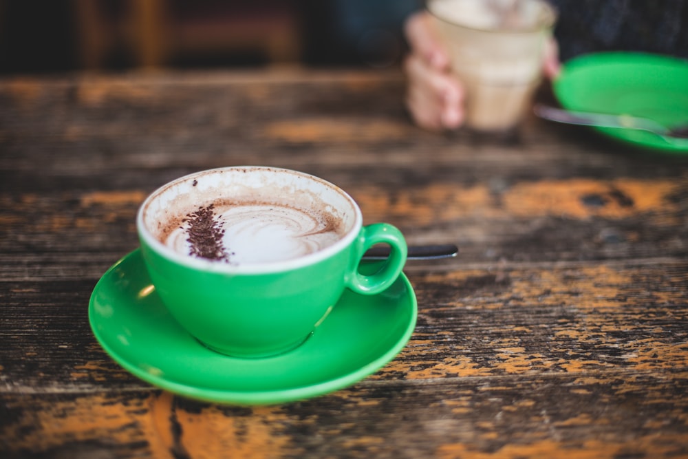 Flachfokusfotografie einer grünen Teetasse mit Kaffee im Inneren