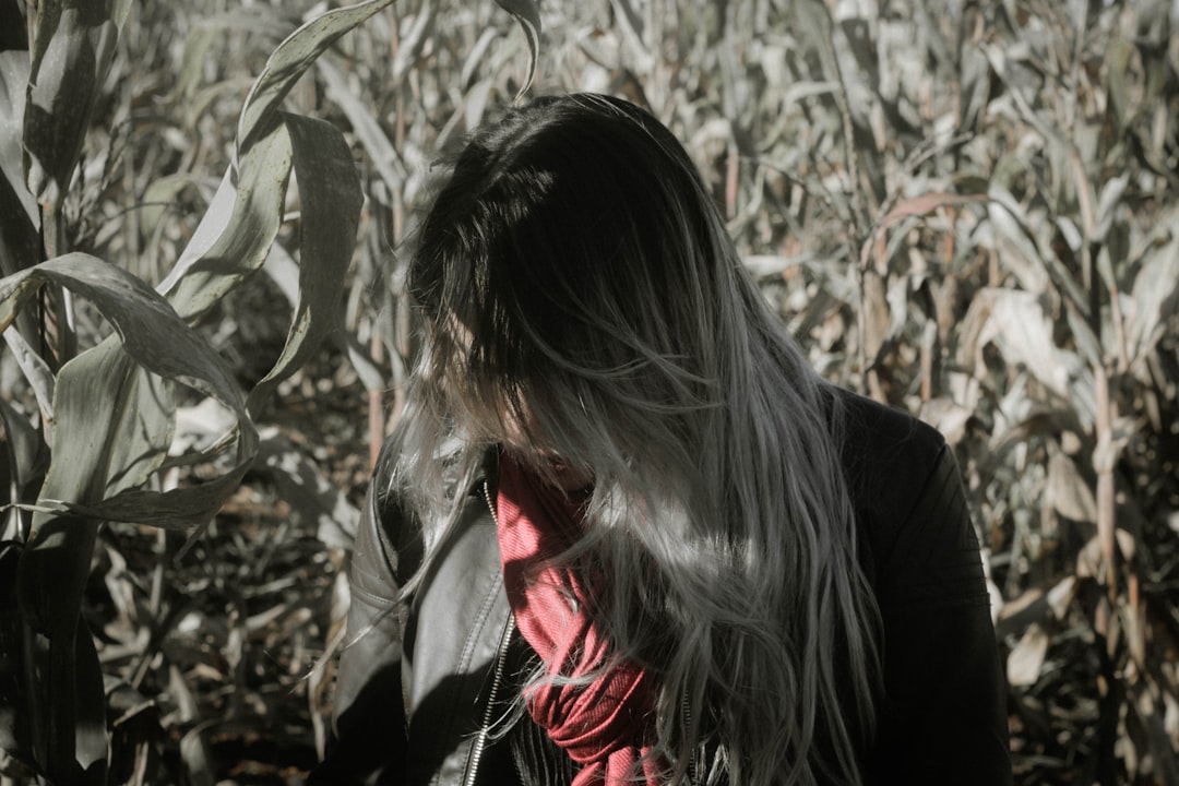 grayscale photo of woman standing beside corn field