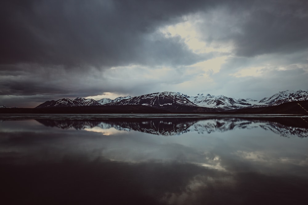 landscape photo of body of water with mountain covered with snow