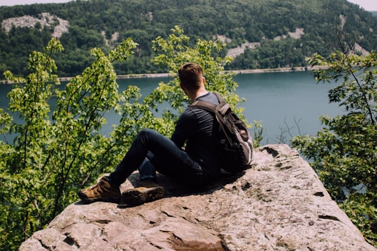 person with backpack sitting on gray rock in Devils Lake United States