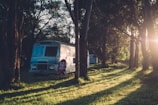 A cozy camper van parked in a sunlit forest clearing with solar panels on the roof.