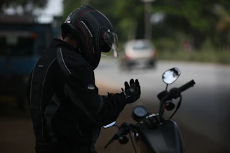 Close-up of a rider gearing up with helmet and gloves beside a rental motorcycle.