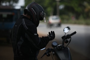 A black-and-white shot of a biker adjusting their helmet before a ride.
