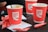 Three red paper cups with the 'Café Coffee Day' logo are placed on a tray. There are also several empty sugar sachets scattered around on white napkins.