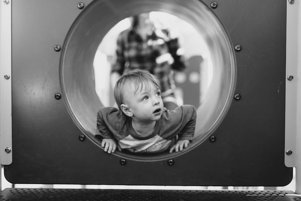 grayscale photo of child in hole