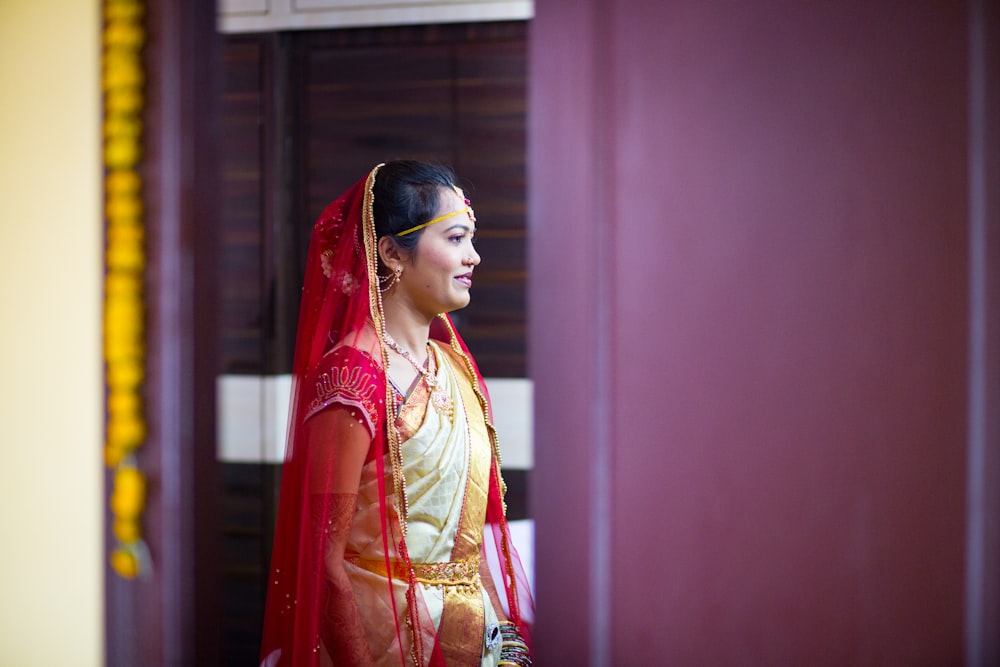 사리 드레스를 입은 여자가 보라색 벽 근처에 서 있다