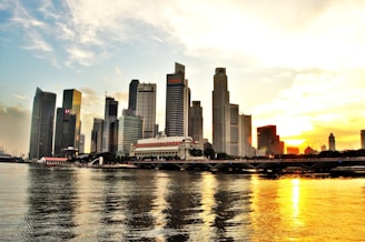A sleek Dubai skyline at sunset with modern skyscrapers and shimmering water reflections.
