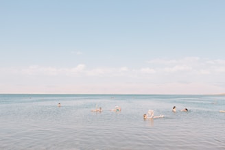 people swimming on sea under cloudy sky