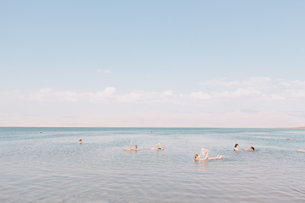 personnes nageant sur la mer sous un ciel nuageux