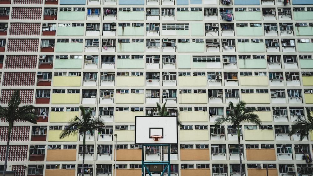 Aro de baloncesto portátil blanco y negro cerca de árboles altos y edificios de hormigón durante el día