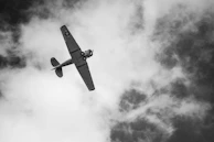 A vintage airplane soaring above clouds with a modern atmospheric filter.