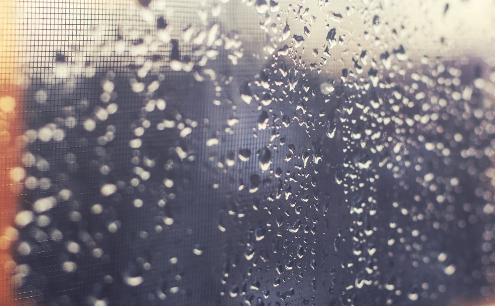 背景がぼやけた窓に雨が落ちる