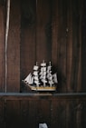 black, brown, and white galleon ship scale model on brown wooden shelf